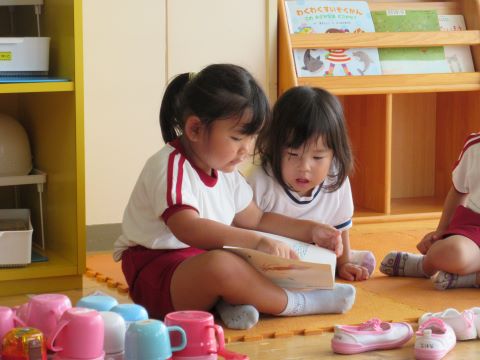 友達と一緒に絵本を見合う園児