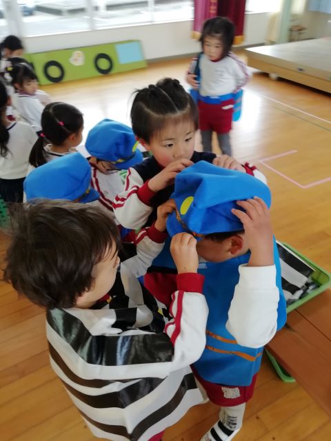 年下の友達に衣装を着せてあげる園児
