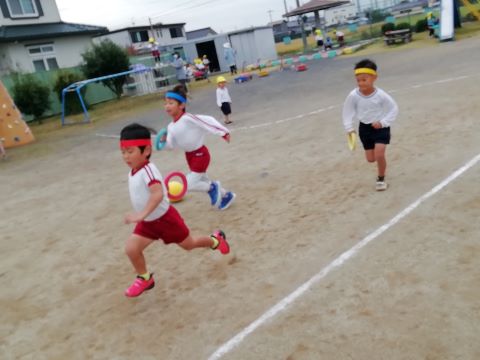 友達とリレーごっこをして遊ぶ園児