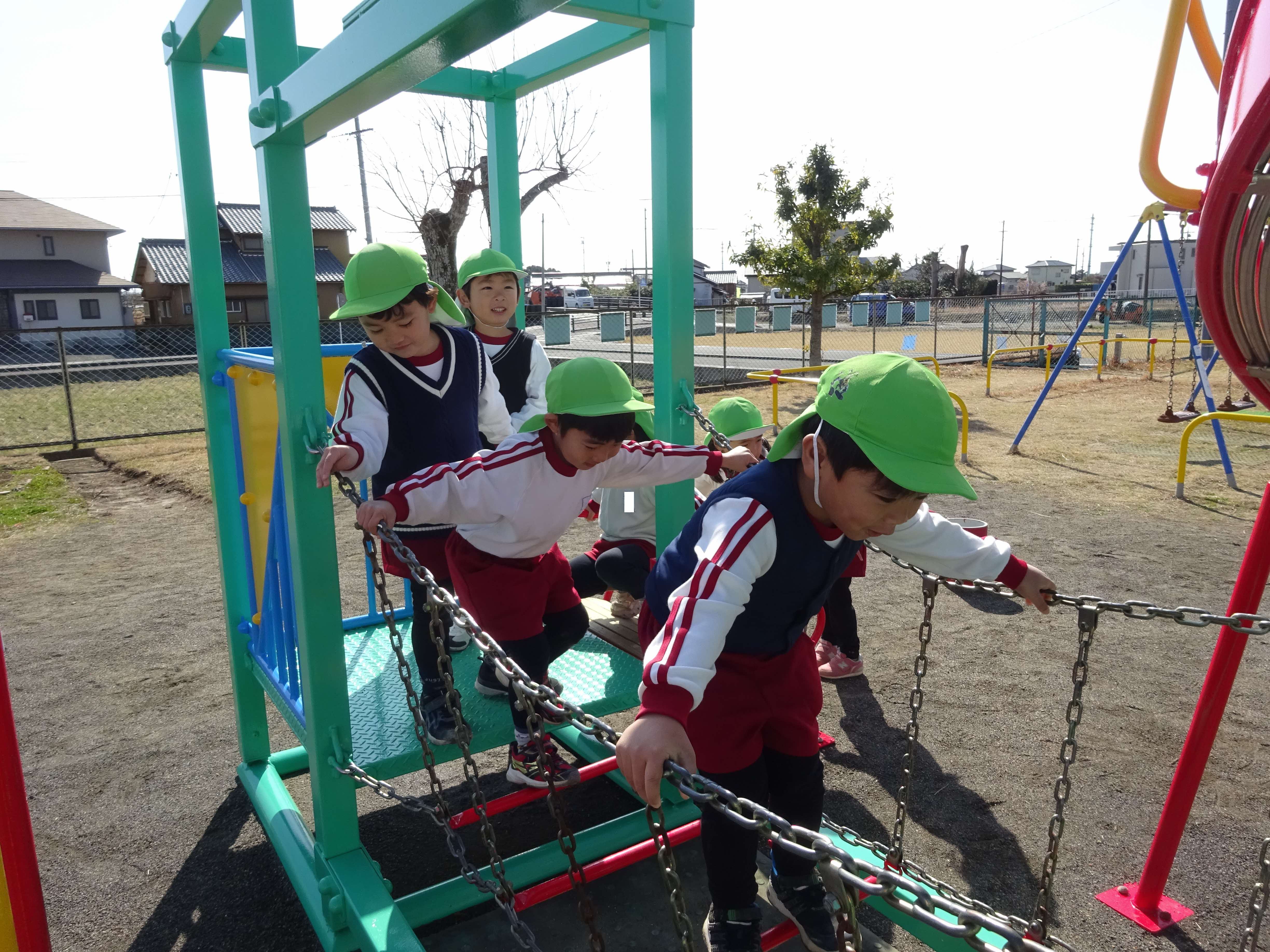 友達と一緒に遊びを楽しむ子 総合遊具で年中組が吊り橋を渡って遊んでいます